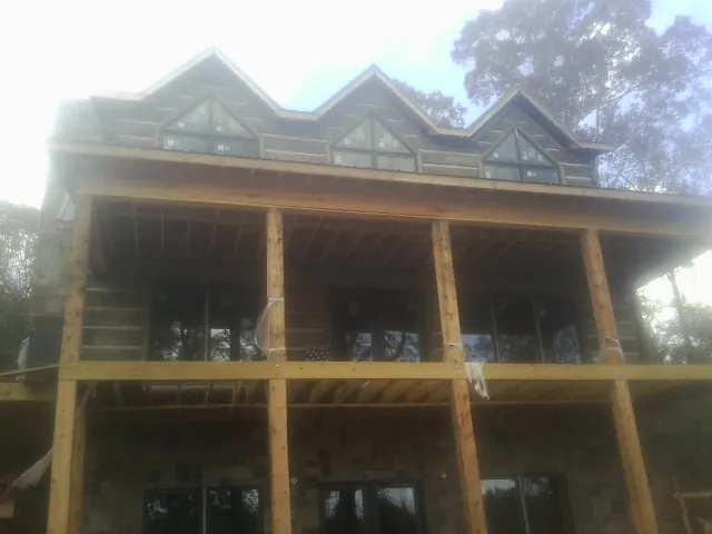Dormers and porch framing on a large log home under construction — Roof Coating work by our crew in Thayer